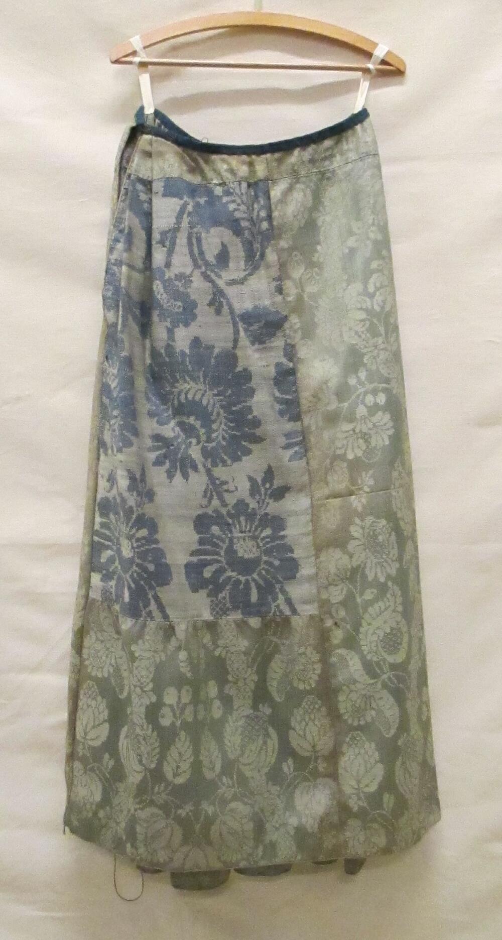 Rok van wollen damast in groen/wit met floraal motief, rechts voor een stuk van blauw/wit wollen…