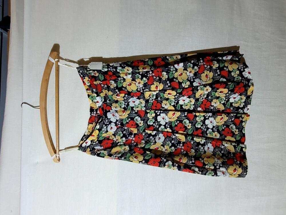 Rok van kunststof met bloemenprint in rood, geel en groen op een zwart fond, wijd uitlopend,…