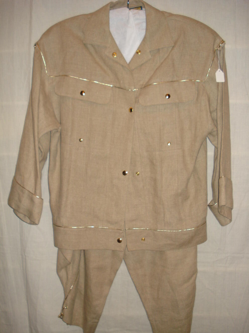 Broekpak van beige linnen versierd met goudkleurige piping, jasje en broek in safari-look