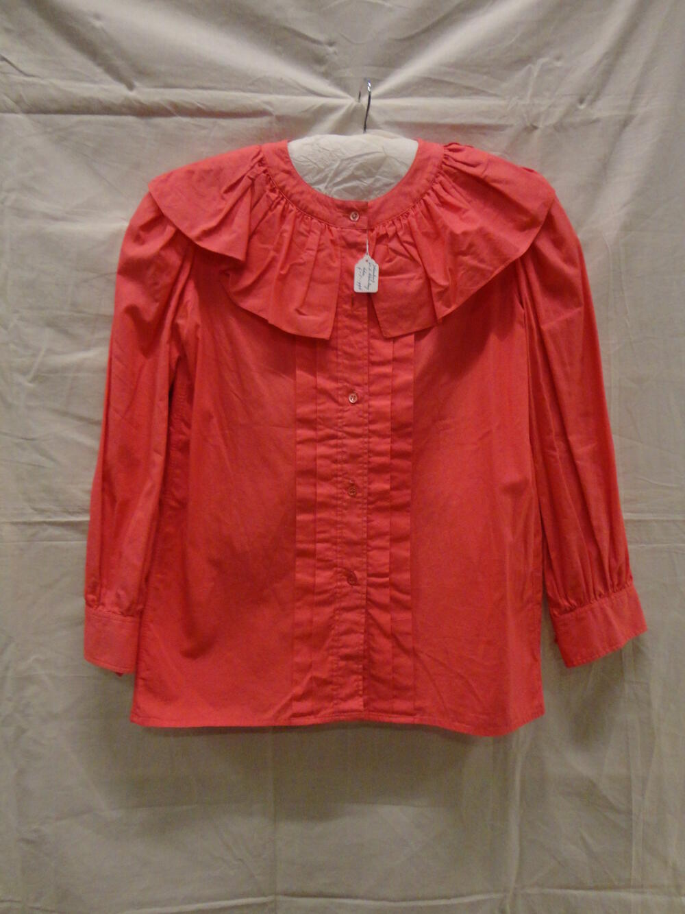Blouse van roze katoen, twee ingestikte plooien aan weerskanten van sluiting