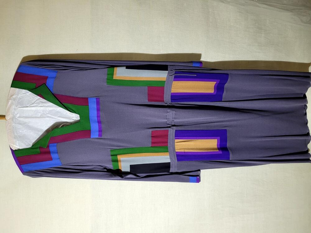 Jurk van grijze stof. Recht model met versiering van veelkleurige geometrische motieven langs hals,…