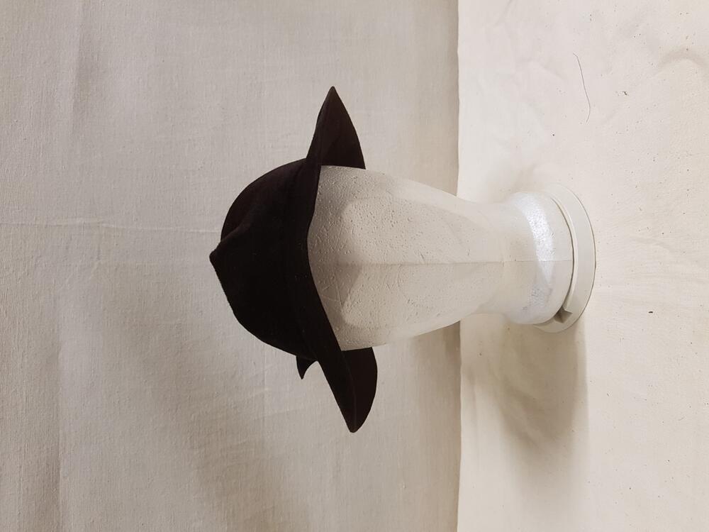 Hoed van bruin haarvilt met aan linkerkant omgeslagen rand. Aan achterkant bladvormige decoratie…