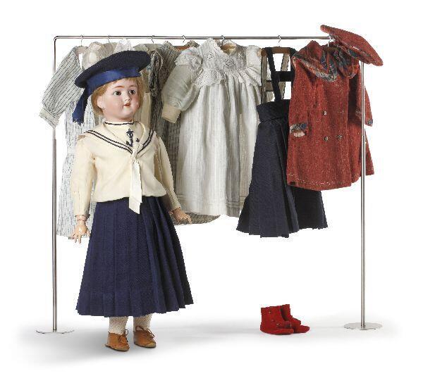Pop met porseleinen hoofd en blonde pruik. Bijbehorende set poppenkleertjes