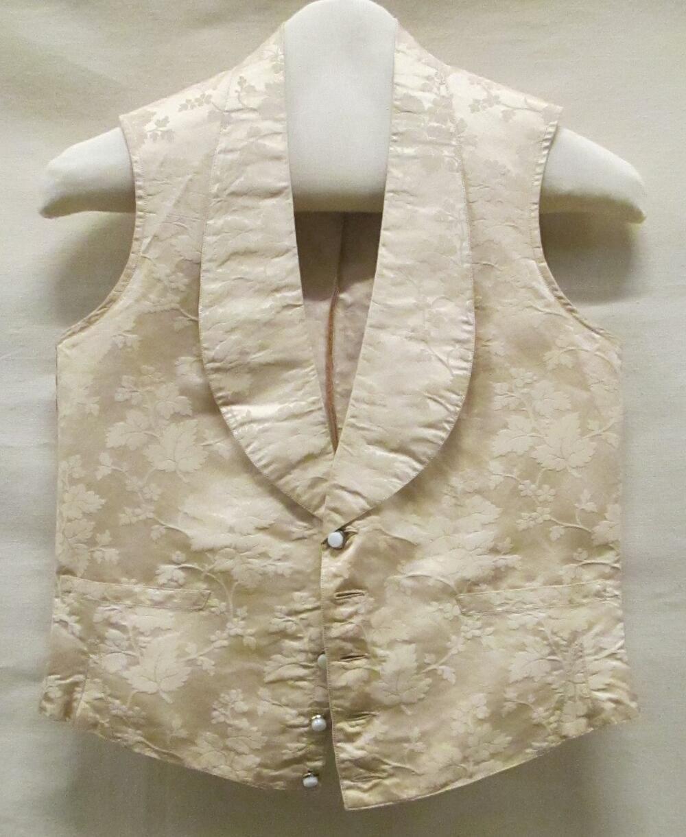 Vest (man) van crèmekleurig damast met ranken van bladeren en bloemen, knopen van wit glas en…