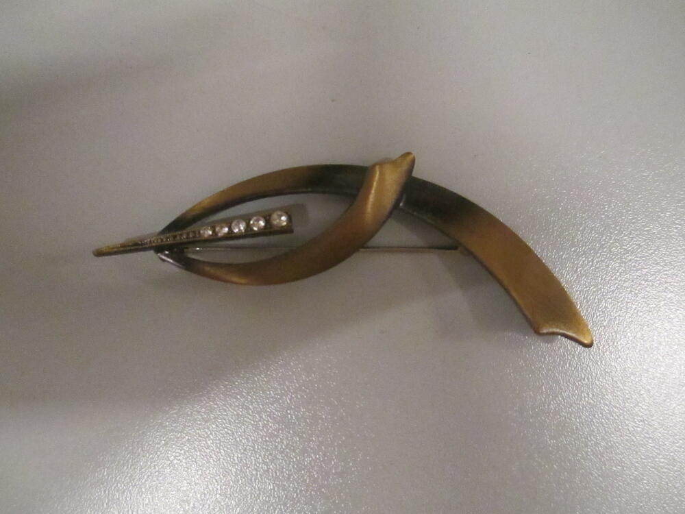 Broche van onedel metaal, deels zwart gelakt en bezet met witte strass-stenen