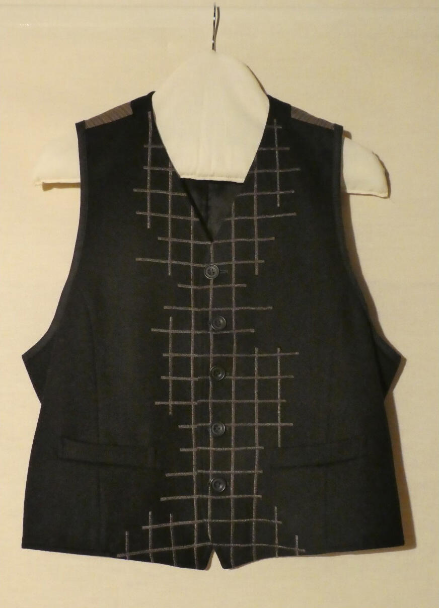 Vest (man) van zwarte stof. Op voorpand bruin asymmetrisch machinaal borduursel in ruitmotieven,…
