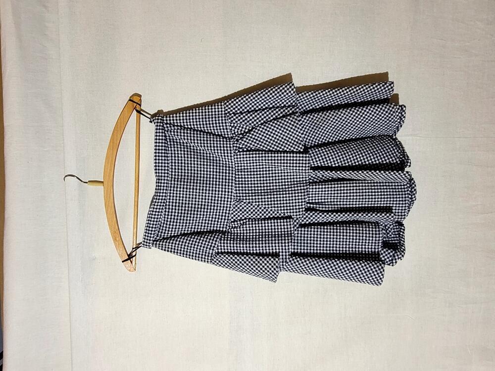 Rok van zwart-wit geruit katoen (seersucker) met tussenstukken van zwart tricot. Halflang model met…