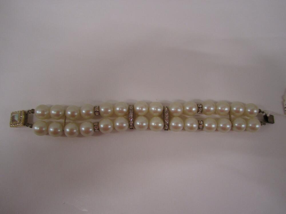 Armband bestaande uit 2 rijen crèmekleurige parels, op 4 plaatsen met elkaar verbonden. In midden 2…
