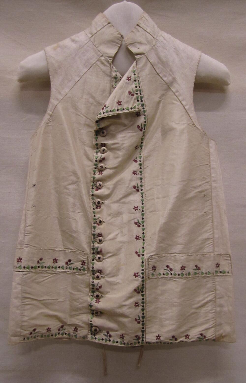 Vest (man) van crèmekleurige zijde. Randversiering van bruine geborduurde bolletjes, achterpand van…
