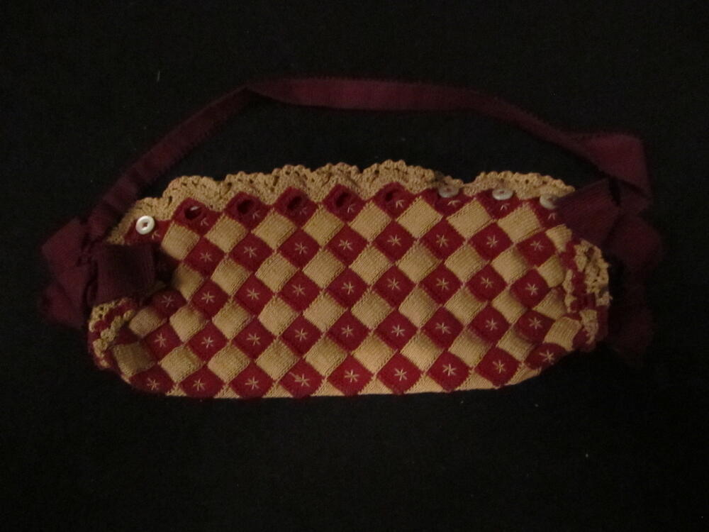 Tasje. Gebreid in blokjes van donkerrood en beige katoen. Sluiting over de lengte met 9 kleine…
