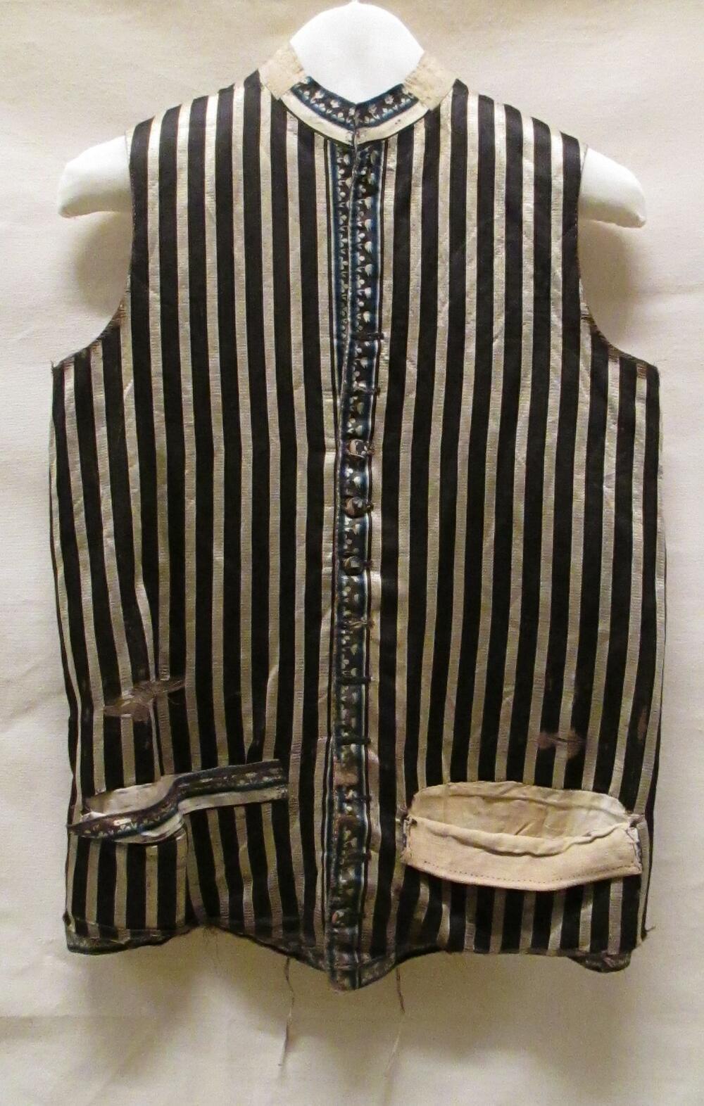 Vest (man) van crèmekleurige/zwarte/blauwe gestreepte zijde, garneringen van blauwe streep en wit…