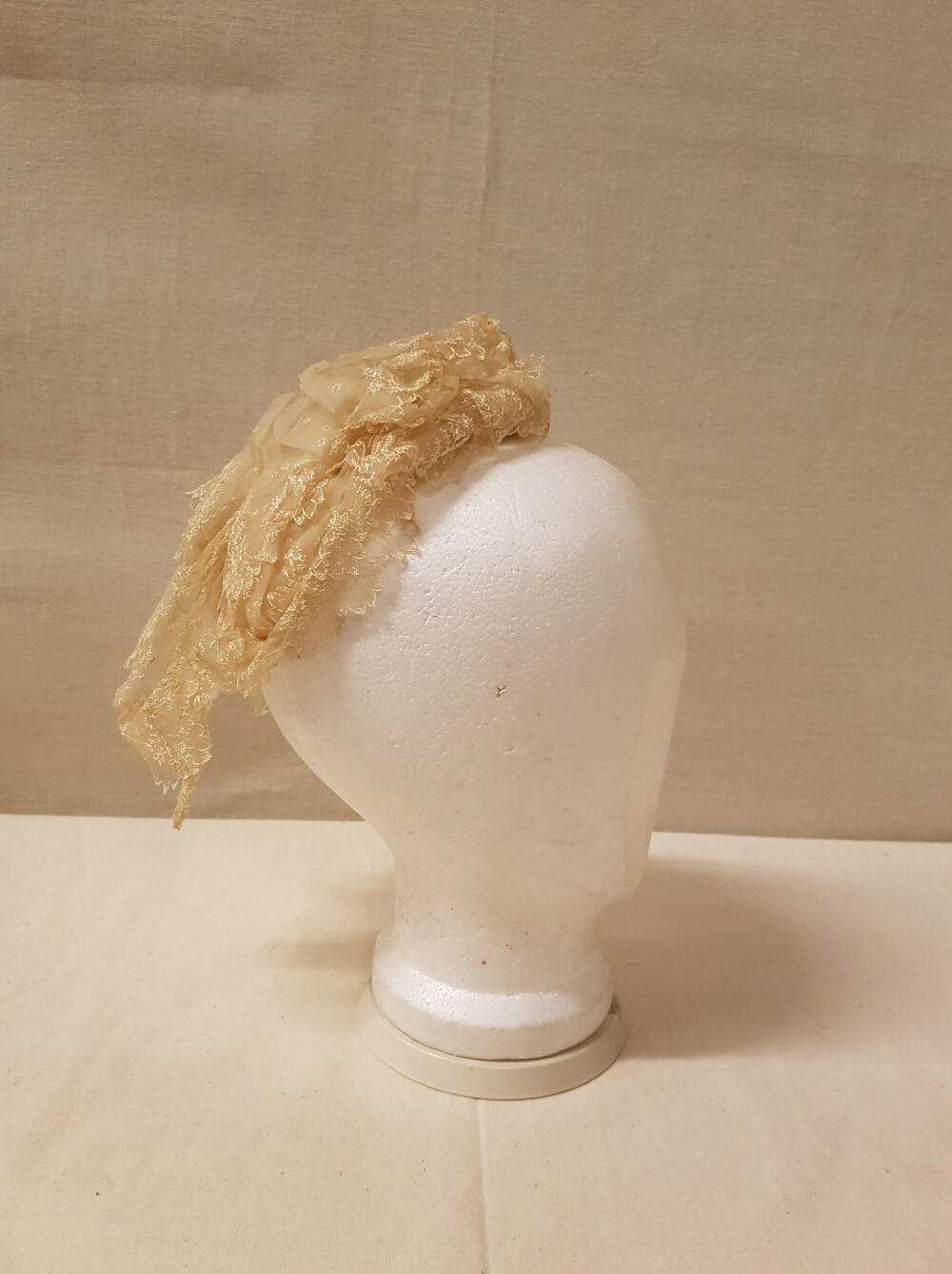 Coiffure / Kap bestaande uit stroken crèmekleurige effen organdie, machinaal geborduurd met…