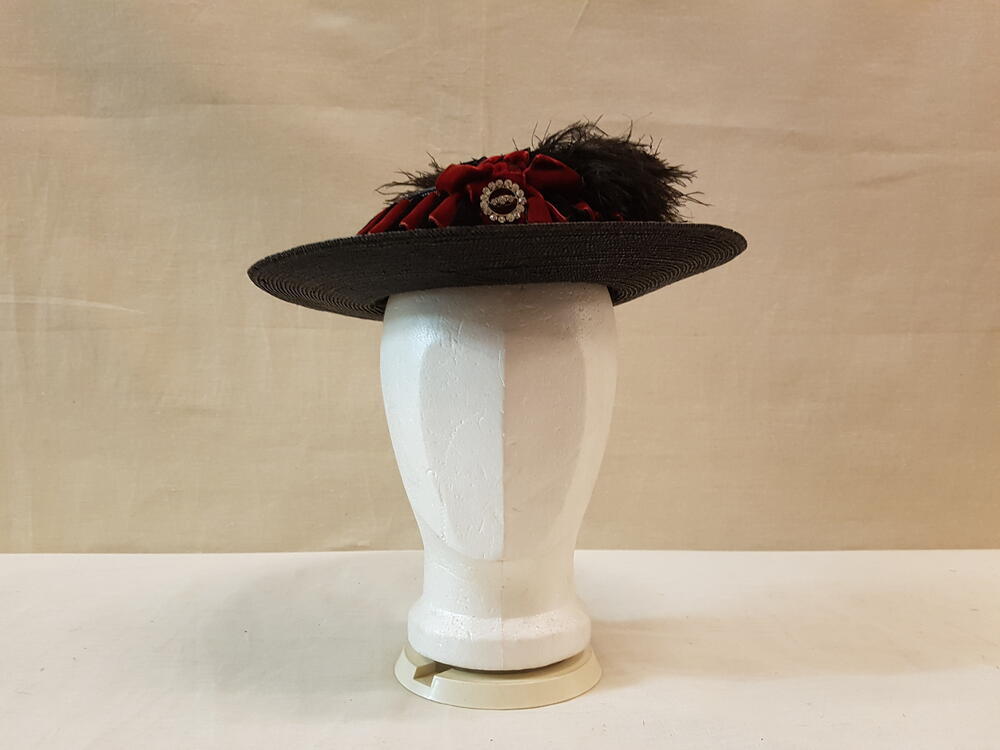 Meisjeshoed, zwart stro, plooisel van zwart met rood fluweelband, bruine struisveer