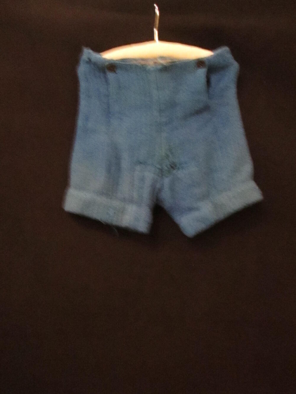 Broek (kind) van blauwe wol. Korte pijpen, aan voorkant klep met twee knopen 2 kunststof