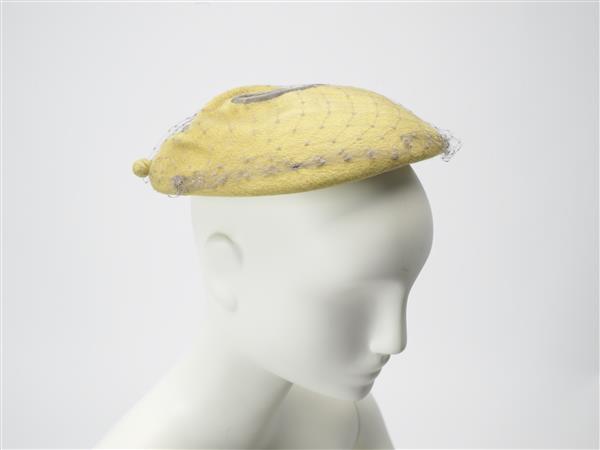 Hoed, plat model in fantasievorm, van geel vilt met voile