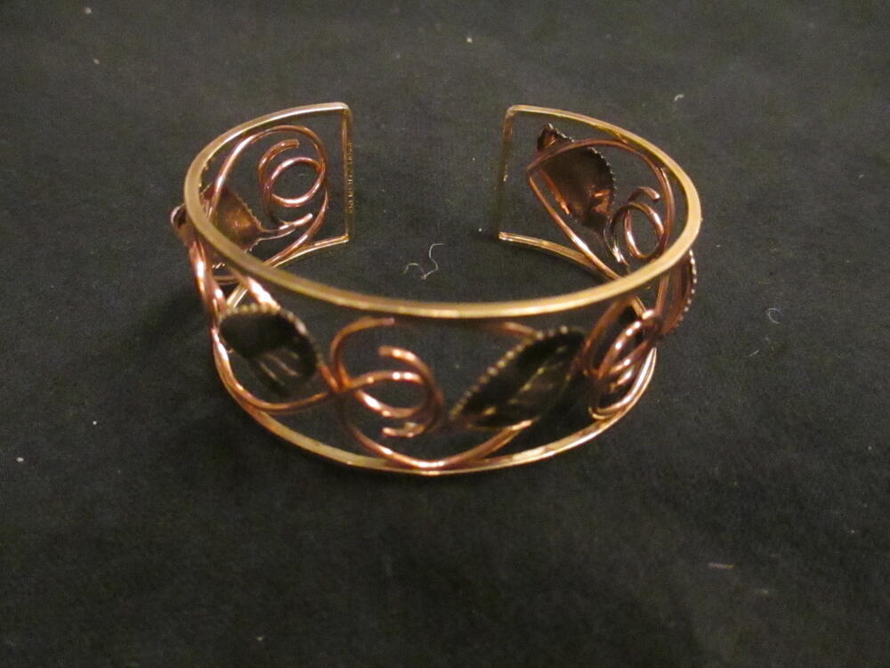 Armband, type 'cuff', open dessin van verguld metaal met koperkleurige krullen en zilverkleurige…