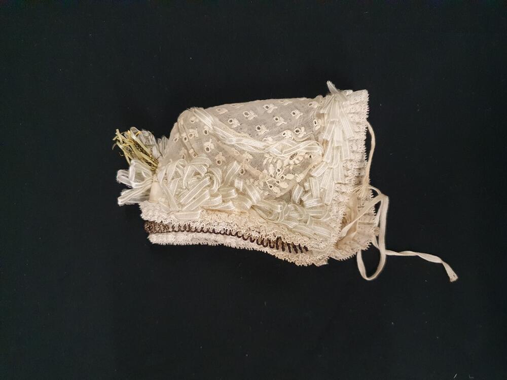 Babymutsje, geborduurd neteldoek, met lichtblauw satijnlint