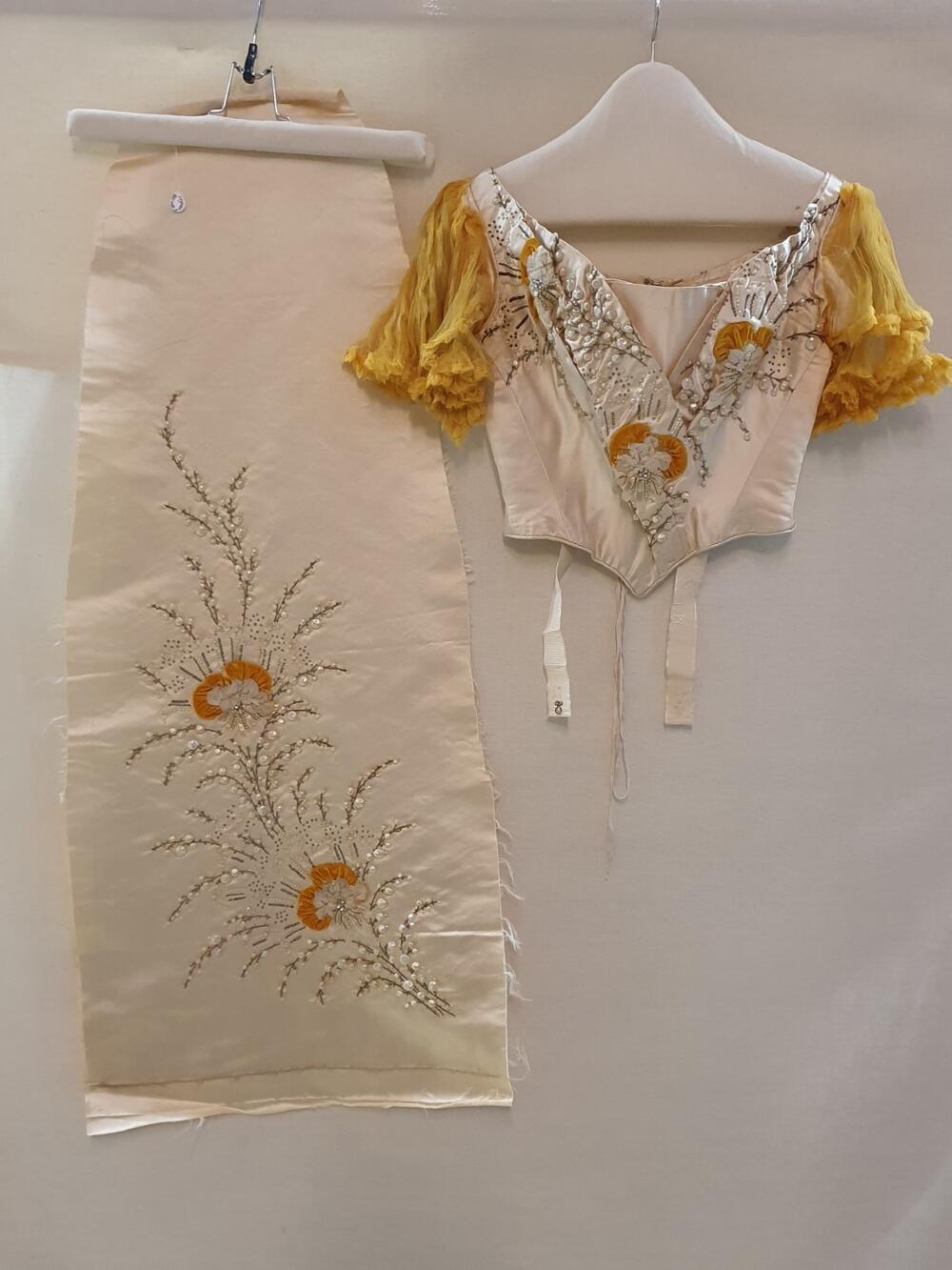 Lijfje en rokbaan van crèmekleurig satijn, gegarneerd met grote bloemranken geborduurd van…
