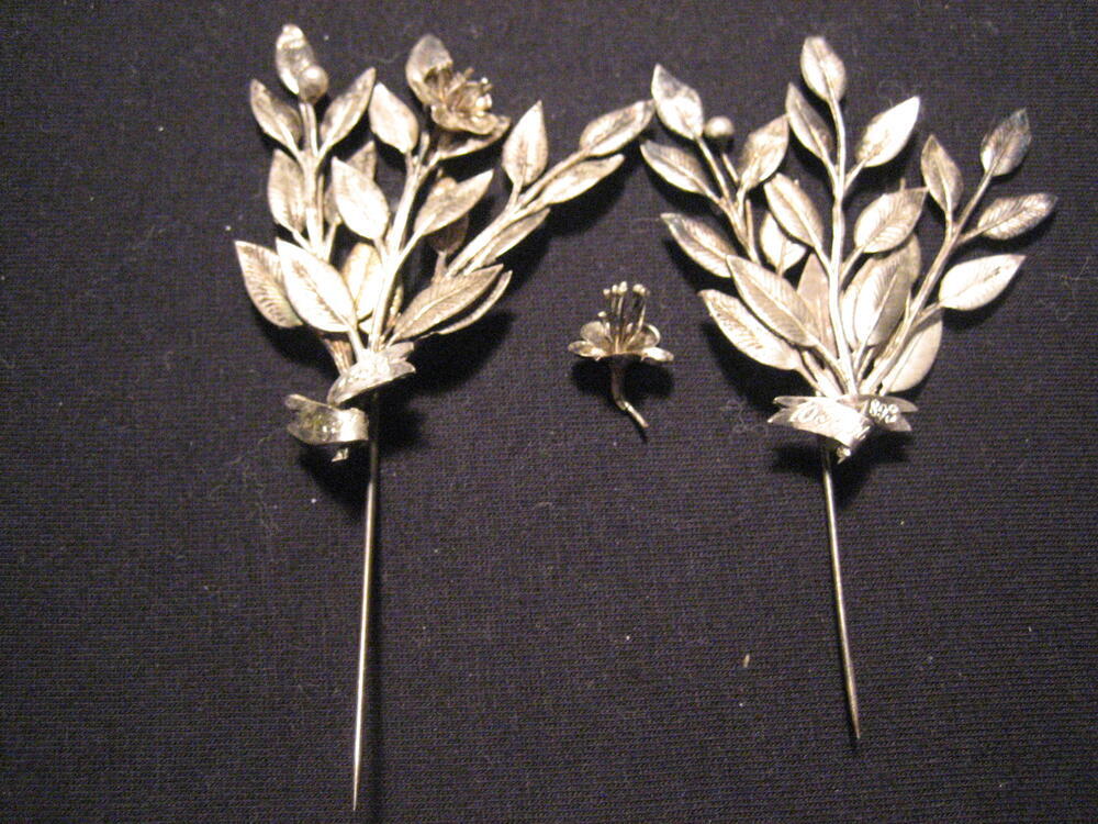 Twee zilveren corsages in vorm van takjes met oranjebloesem