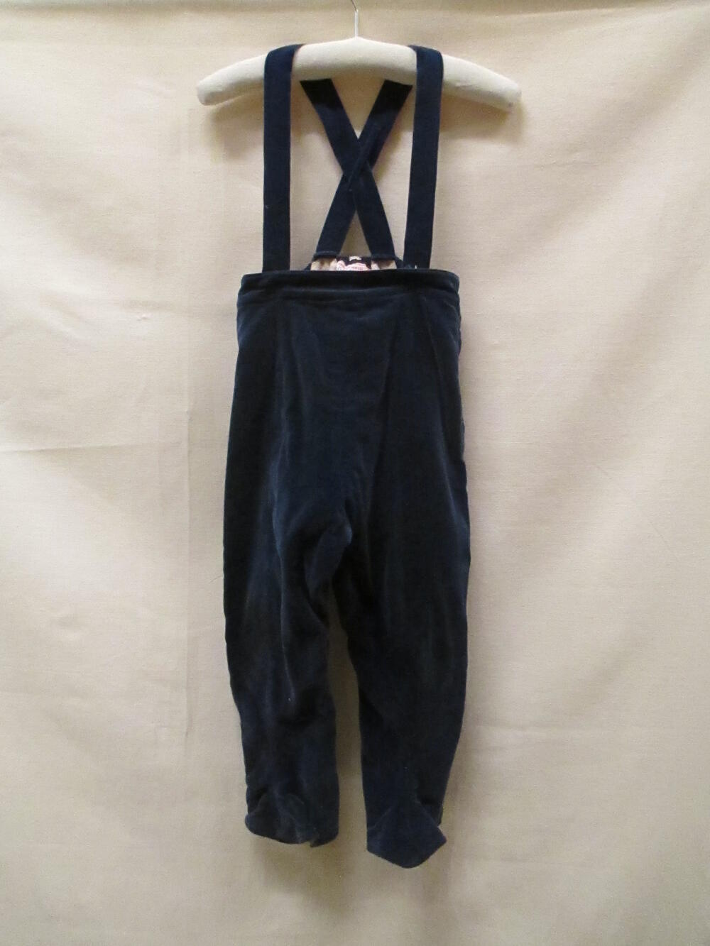 Broek (meisje) voor de winter van blauw fluweel met bretels en voetbandjes. Onderdeel van ensemble