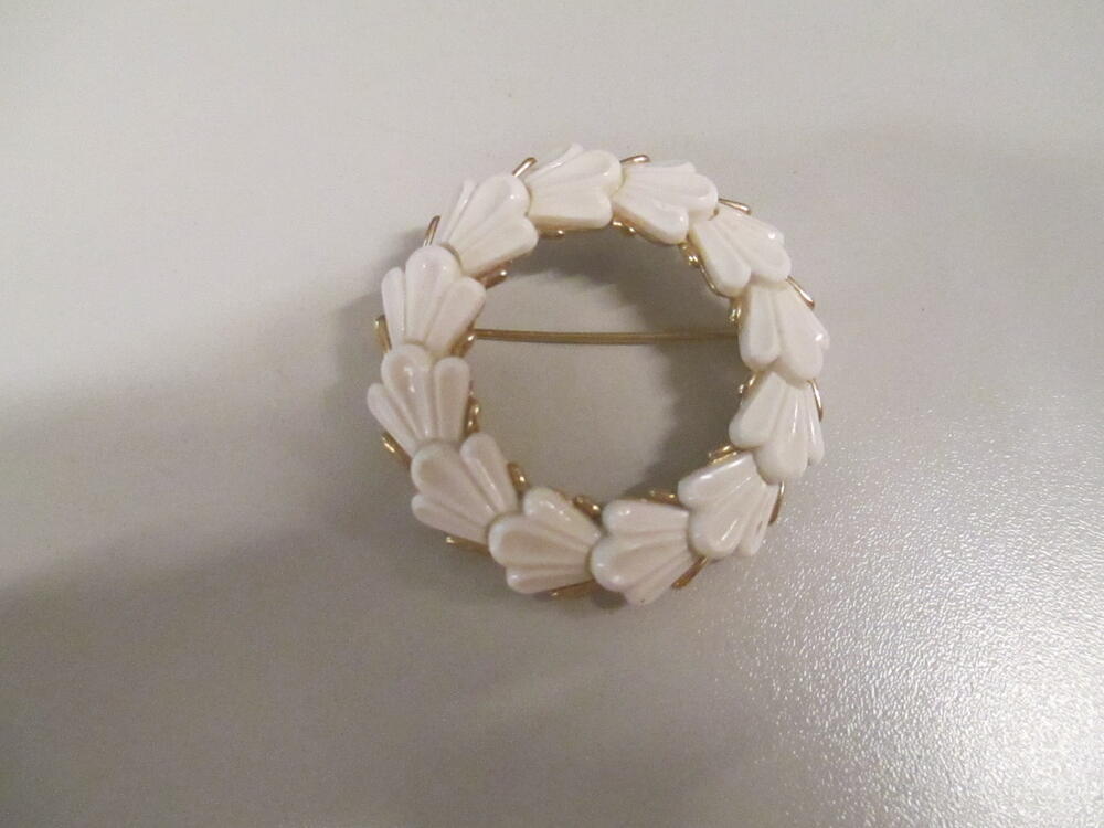 Broche, kransvormig model, zetting van goudkleurig metaal waarop overlappende 'bladeren' van witte…
