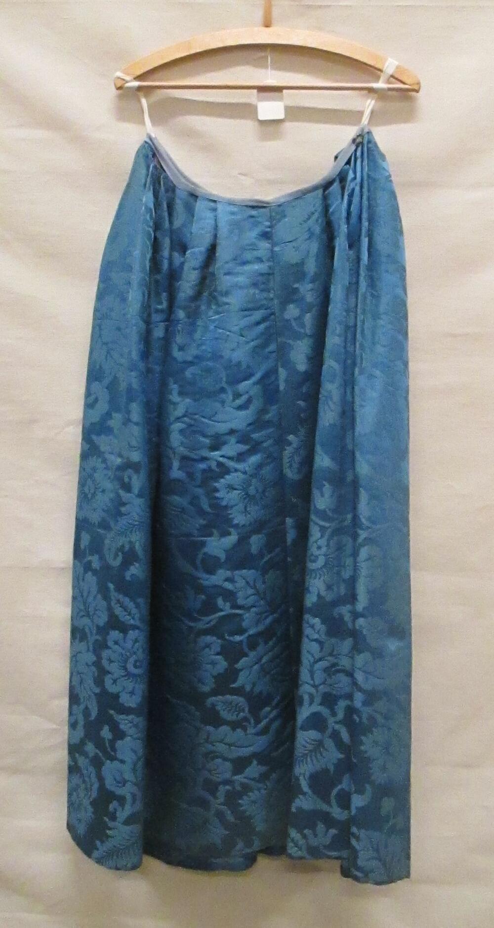 Rok van helderblauw zijden damast met groot ingeweven bloemmotief, smalle rokband van lichtblauw…