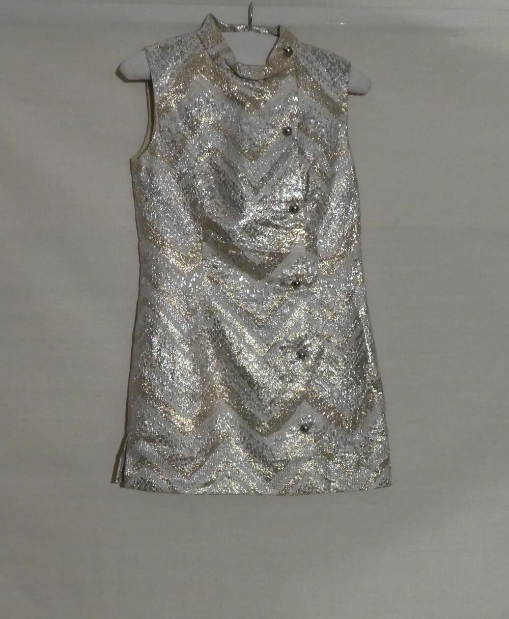 Tuniek in brokaat weefsel met wit fond, ingeweven zilver- en gouddraad in V-vorm. Mouwloos model…