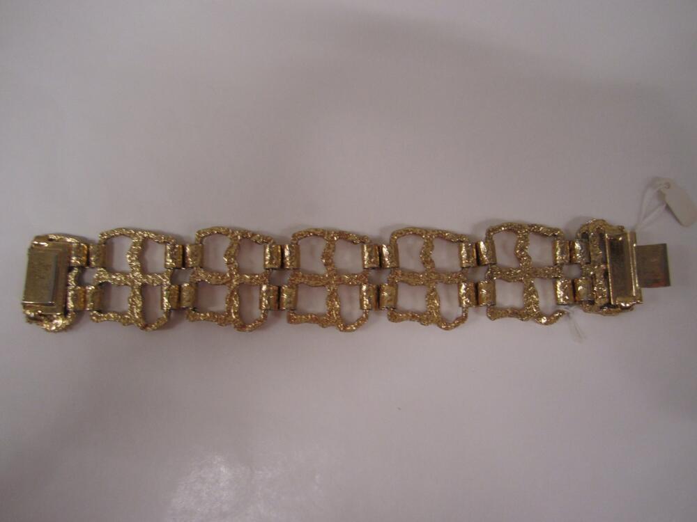 Armband. 5 vierkanten van goudkleurig metaal, aan elkaar bevestigd door 4 goudkleurige omgekrulde…