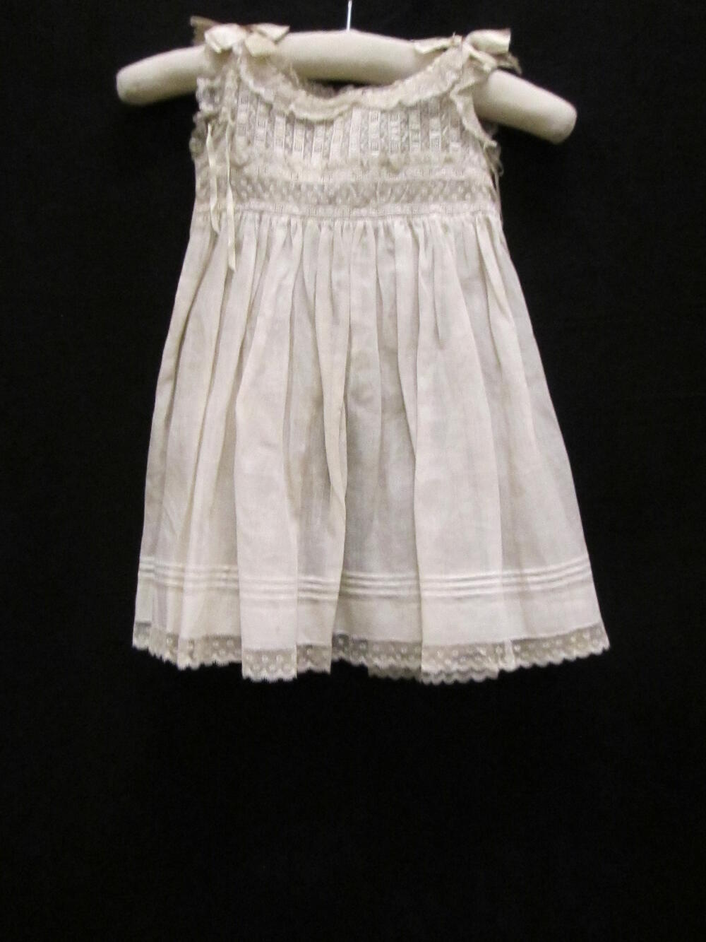 Schort (vrouw/kind) van wit katoenbatist met garnering van machinaal kant en machinale broderie