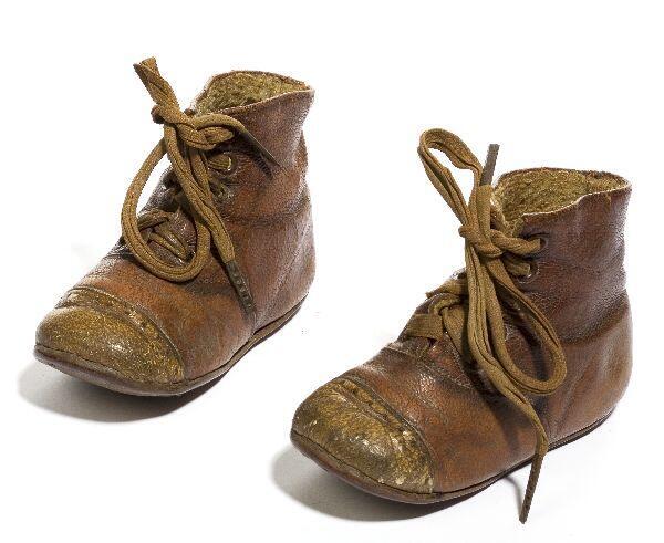Een paar schoenen (kind) van bruin leer met vetersluiting midden voor