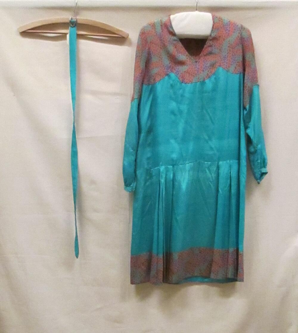 Jurk van turquoise zijde, op schouders en langs de rok zoom veelkleurige zijde bedrukt in…