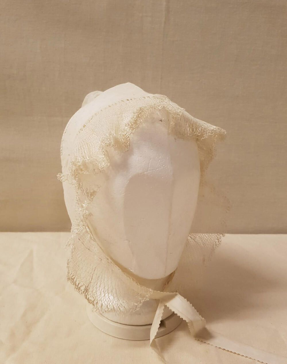 Damesmuts, wit neteldoek met tamboereerwerk (nopjes), rondom de muts ruche van filetwerk