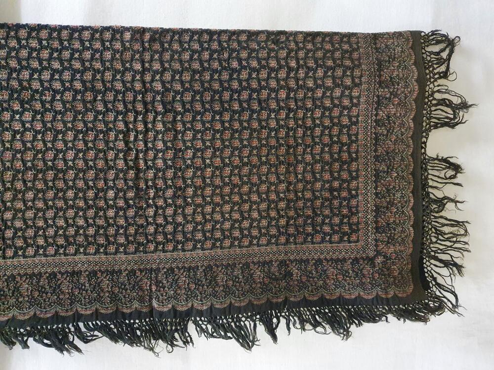 Doek van wol. Zwart fond met bloempjes in rood, vaalgroen en wit