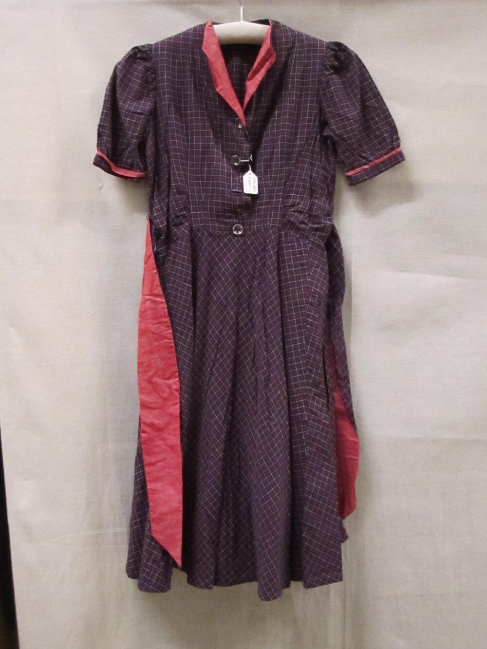 1) Jurk (meisje) van rood/wit/blauw geruit katoen. Korte mouwen, revers van roze rode katoen, wijde…