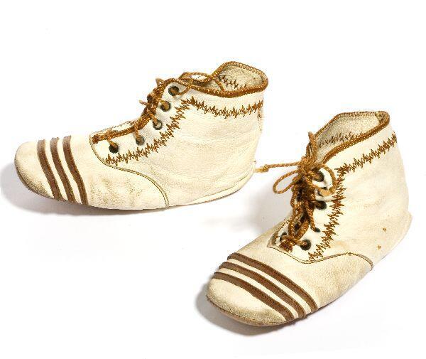 1 paar babyschoenen van crêmekleurig leer. Neus gedecoreerd met 3 stroken bruin leer