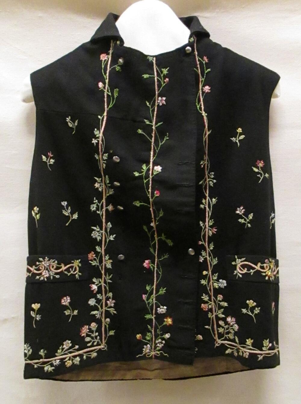 Vest (man) van zwart laken met randborduursel van veelkleurige bloemenslingers en strooimotief,…