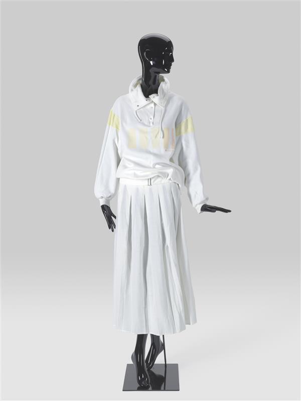Set, bestaande uit lichtgeel/wit sweatshirt, plooirok met ceintuur en slobkousen gedragen met witte…