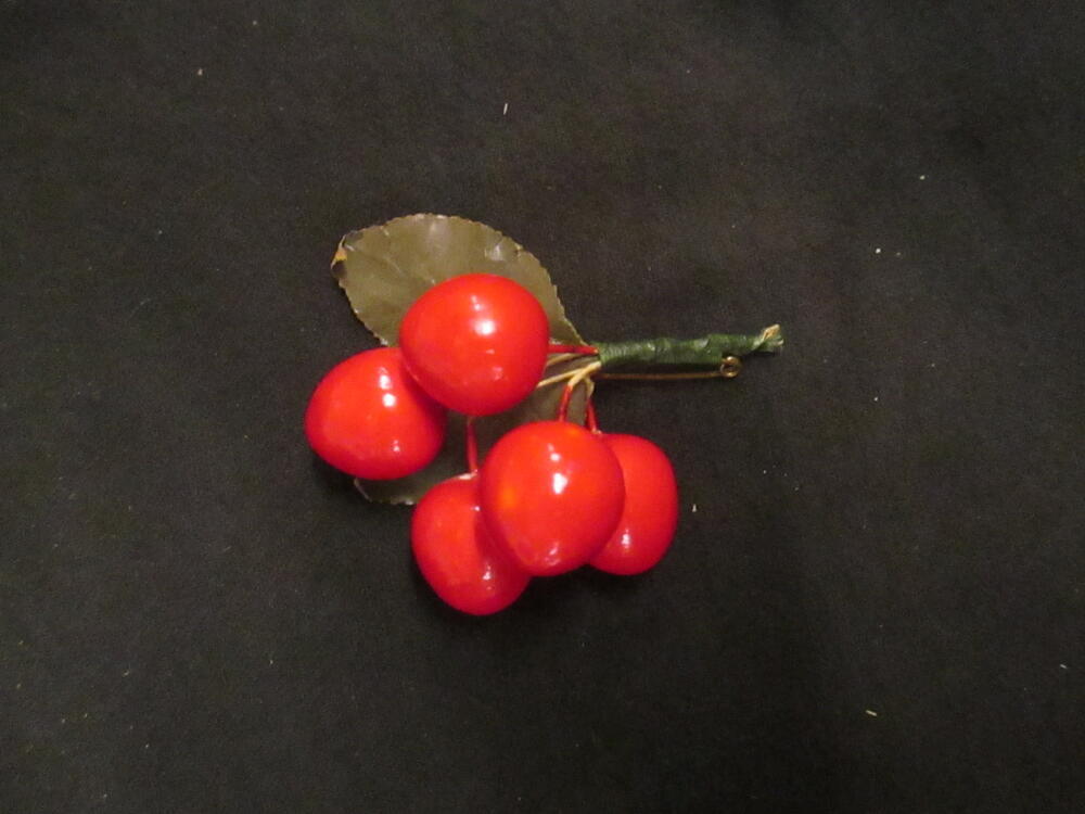 Fruitcorsage, vijf roodgelakte houten kersen en twee groene blaadjes, gevat in groen omwikkeld…