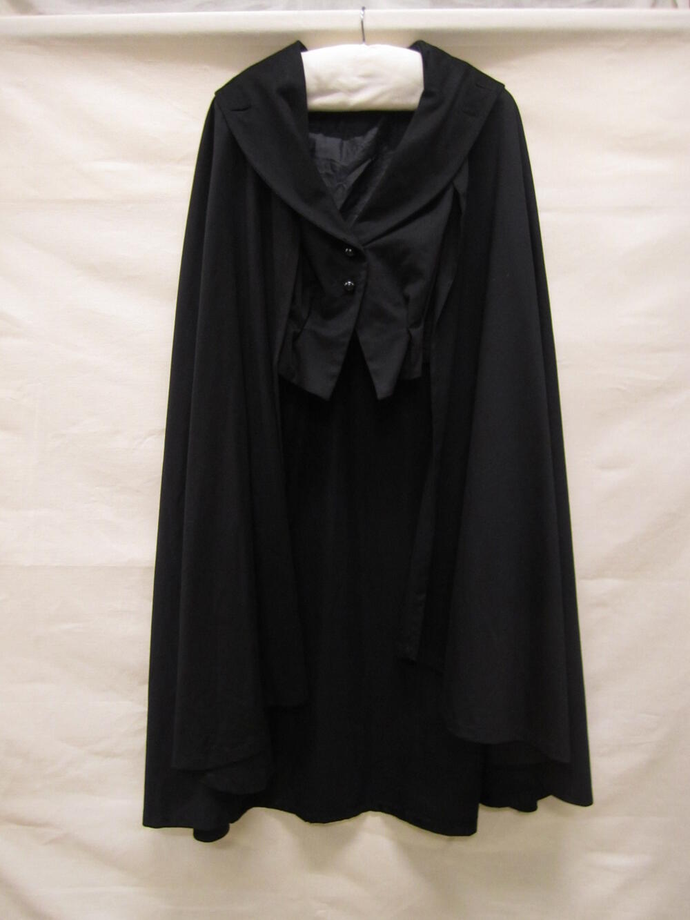Cape van zwarte wol zgn. laken, wijd model, kuitlang, met vierkante kraag en knoopsluiting, hierbij…