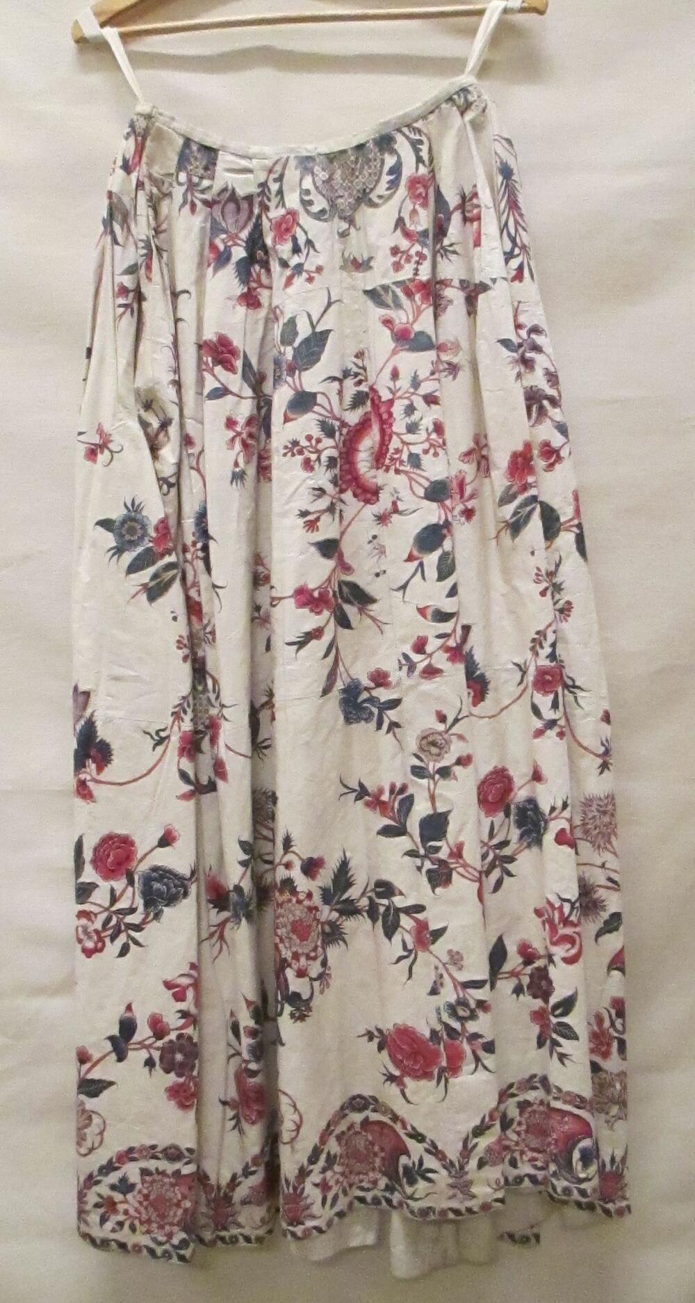Rok van witte sits met handbeschilderde bloemranken in rood, blauw, roze, geel en paars, langs de…