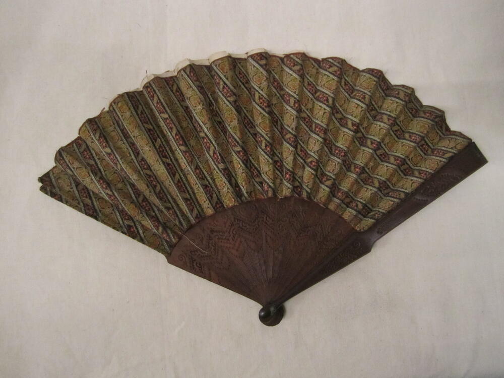 Vouwwaaier, montuur van bewerkt bruin hout, blad van veelkleurig pluche met patroon van diagonale…