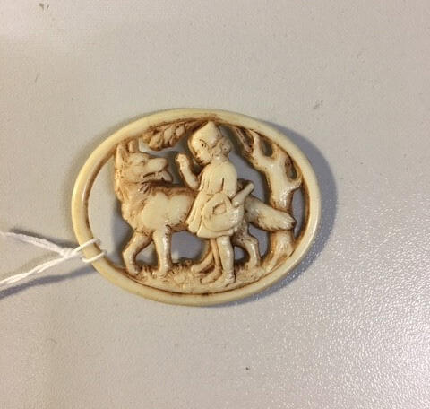 Onderdeel van broche, ovaalvormig ajourgesneden been met voorstelling van Roodkapje en de wolf