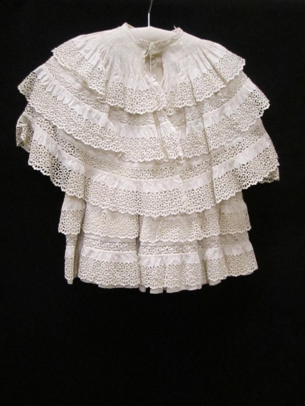 Jas (kind van wit katoenen piqué met broderie / Mantel (kind) van wit piqué met pelerine van wit…