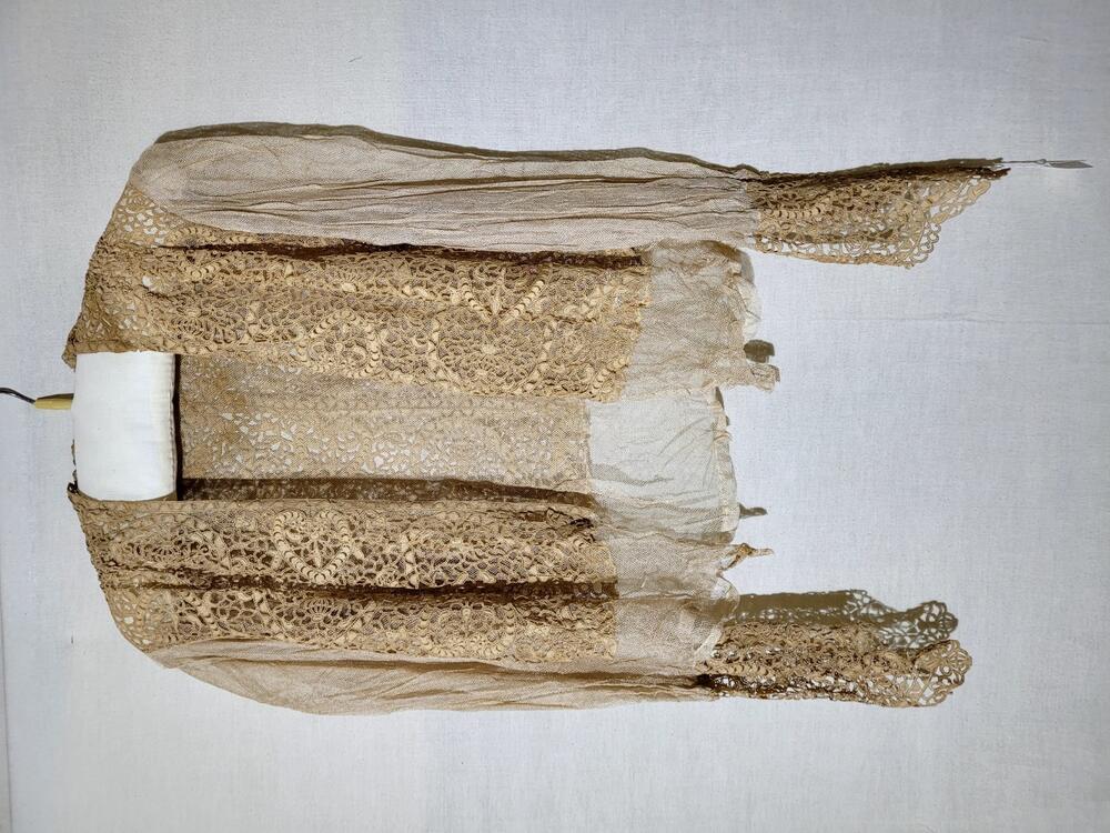 Blouse van beige machinaal kant op ondergrond van beige tule