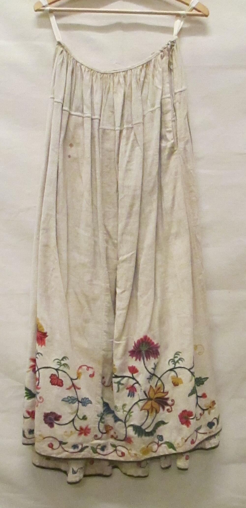 Rok van crèmekleurig linnen in keperbinding, langs de zoom veelkleurig crewelwork in…