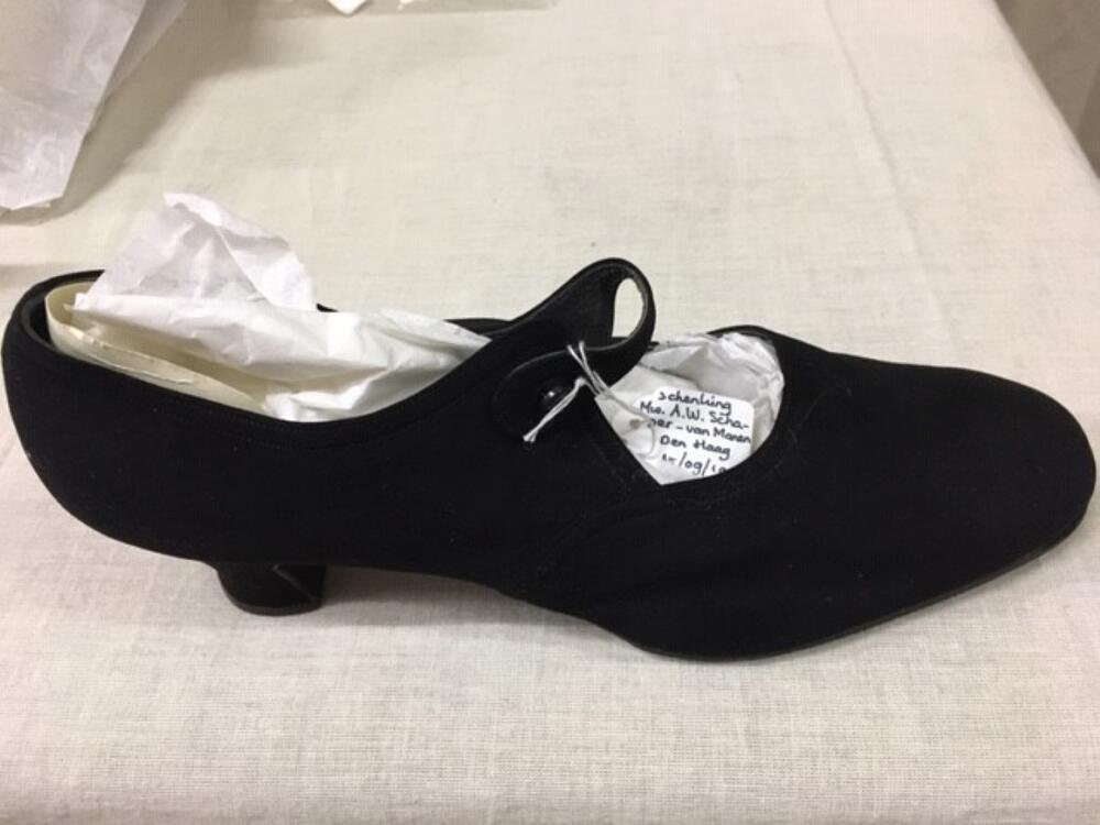 1 paar schoenen van zwart suède. Ronde neus, bandje over wreef bevestigd over zwarte knoop, hoge hak