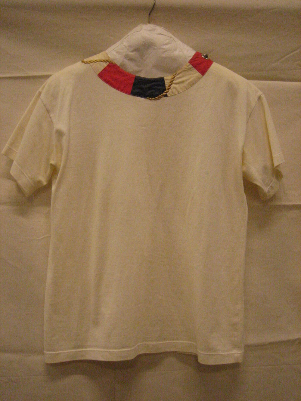 T-shirt van gebroken wit tricot met korte mouwen, hals afgezet met rood, blauw, witte bies met…