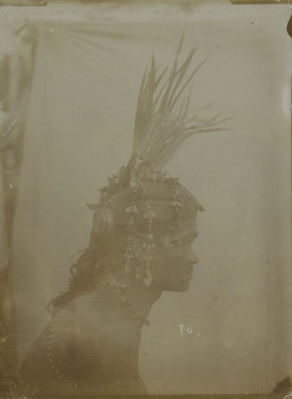 Portret van een Dajak man op Borneo met een hoofdeksel met kralen, ornamenten en veren