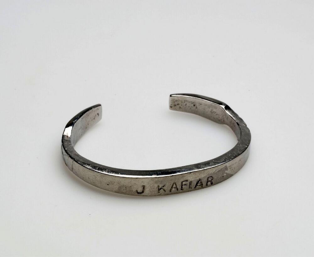 Armband van vliegtuigstaal, voorzien van ingegraveerde naam J. Kafiar