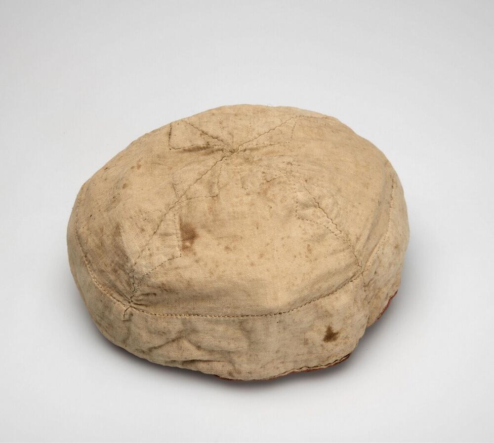 Wit katoenen kindermutsje met rood randje